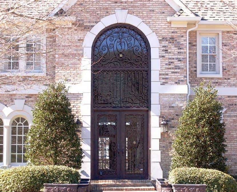 Grand double wrought iron door EL1124 MCD with tall glass panels, intricate scrollwork, and an ornate full-height arched transom.
