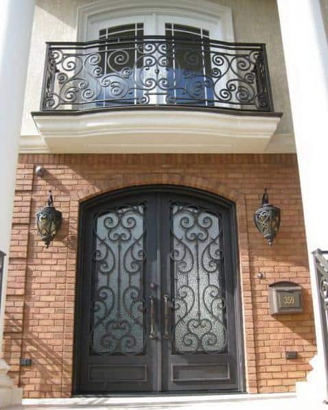 Arched double wrought iron door with decorative grillework, beveled glass panels, and solid lower panels.