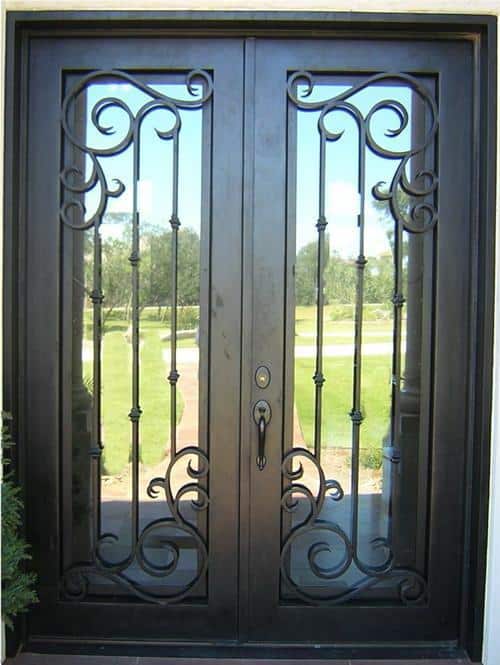 Contemporary double wrought iron door with tall glass panels, vertical bars, and symmetrical ornamental scrollwork.