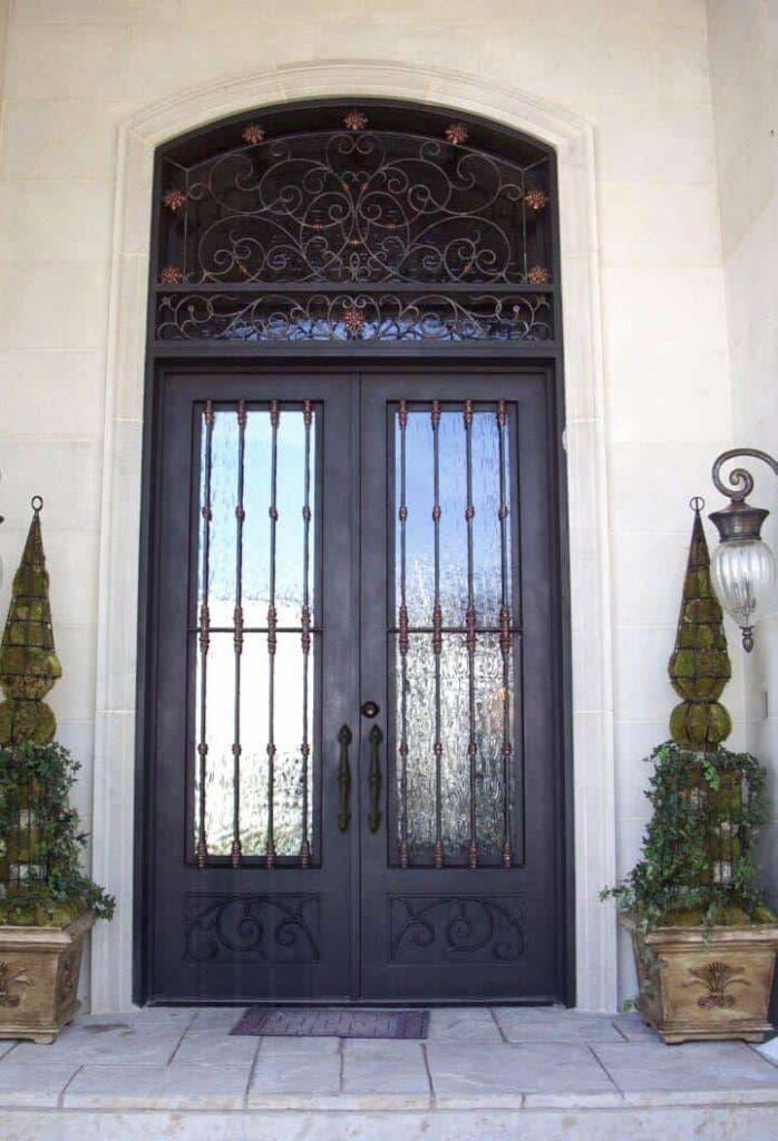 Double wrought iron door with tall glass panels, vertical ironwork and an ornate scrollwork transom, EL1111 MCD by Monarch Custom Doors.