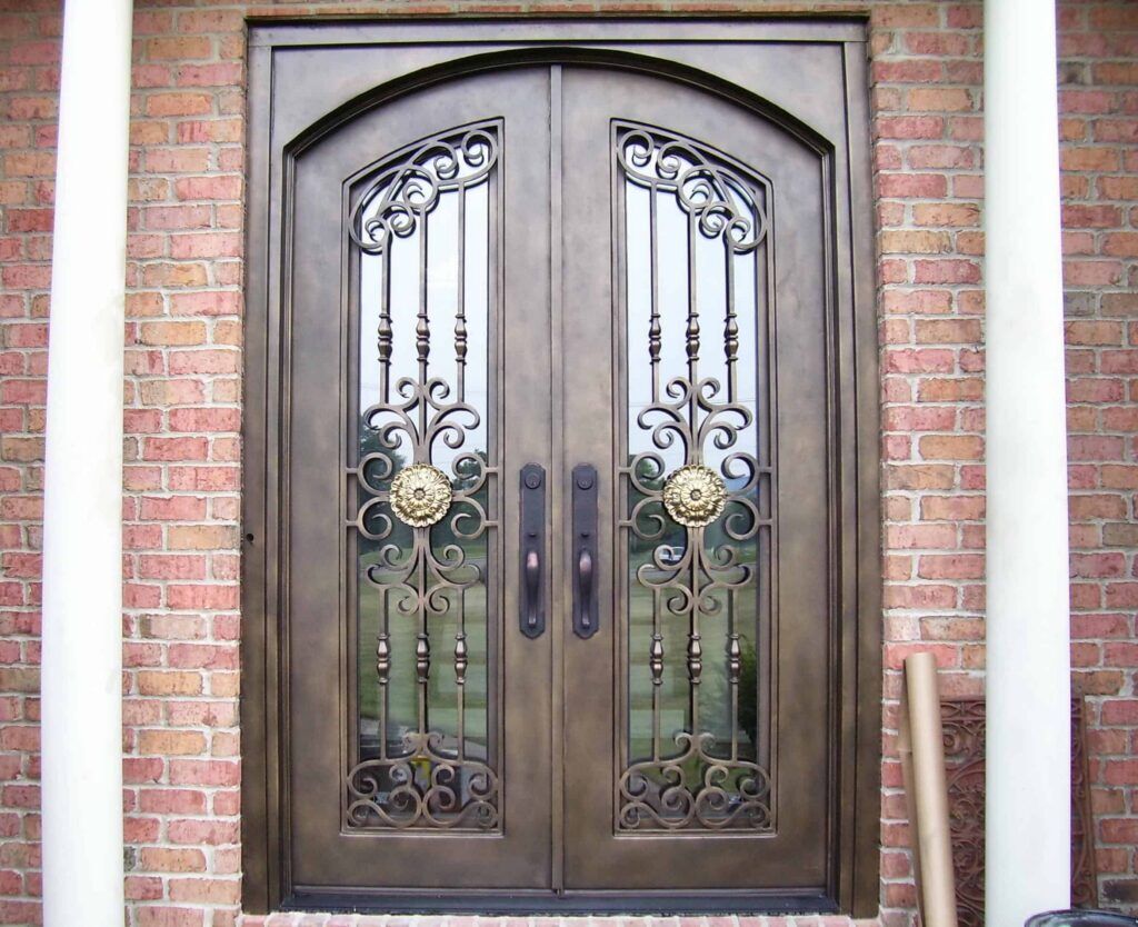 Double arched wrought iron door with sculpted floral rosettes, ornate scrollwork and decorative glass EL1107 MCD by Monarch Custom Doors.