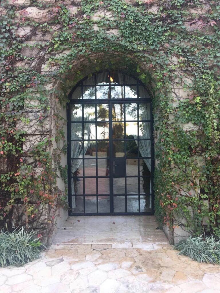 Arched double wrought iron door EL1166 MCD featuring full-height glass panels plus geometric grid mullions in a divided-light design.