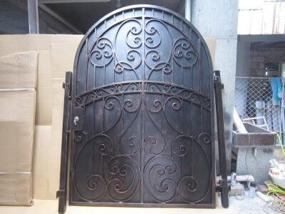 Arched wrought iron gate with decorative scrollwork and solid privacy panel design G115 MCD
