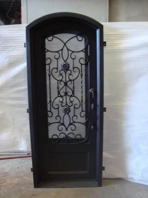 Single arched wrought iron door EL1080 MCD with scroll centerpiece and glass, handcrafted for strength and elegance.